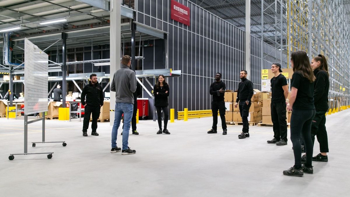 Employees in different roles discuss operations at a logistics warehouse